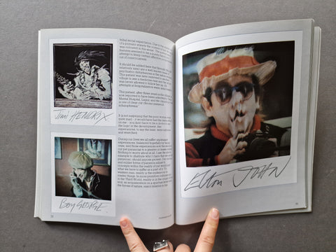 An open book showing a big distorted polaroid of Elton John on the right and two smaller distorted polaroid portraits on he left - Jimi Hendrix and Boy George