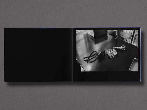 A spread of a book showing a still life photograph of a camera and ashtray on a table