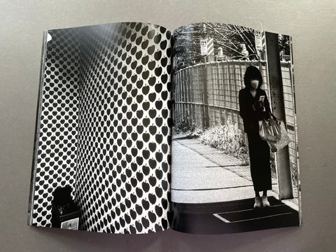 Open book with black and white patterned cover and photo of a person on a sidewalk.