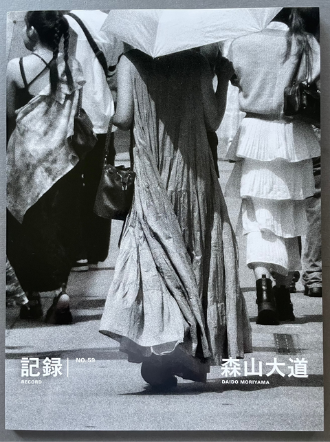 Front cover of Record No.59 by Daido Moriyama with a black and white image of a woman holding an umbrella on a street.