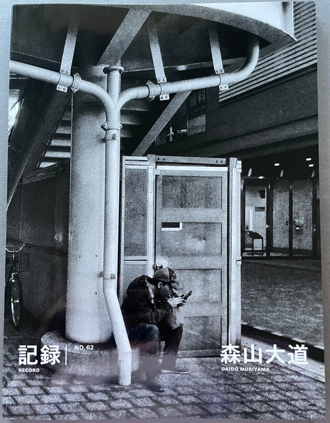 Front cover of Record No.62 by Daido Moriyama with a black and white image of a street scene with a man watching his phone.