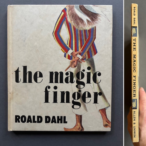 Book titled 'The Magic Finger' by Roald Dahl with a with cover and the illustration of the back of a girl pointing her index finger.