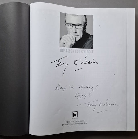 An open book showing the printed cover page with a black-and-white portrait of Terry O'Neill, his signature, and handwritten note on a white page.