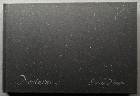 Book titled 'Nocturne' by Sakiko Nomura with a black cover with white specks.