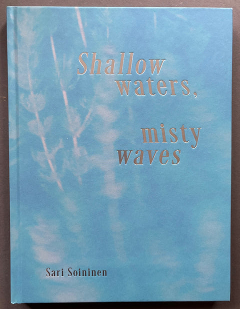Book titled 'Shallow Waters, Misty Waves by Sari Soininen with a blue cover and silver type.