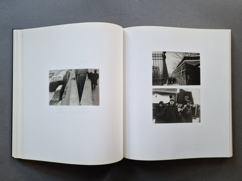 An open hardcover book, showing two printed black-and-white photo panels on the right page and one b&w panel on the left