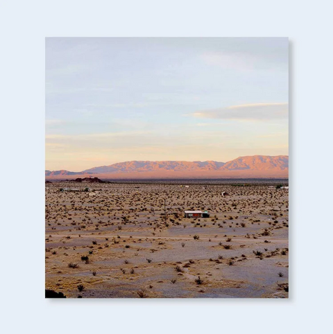 Book titled 'Isolated Houses' with a cover featuring a colour photograph of a desert landscape with a lone house in the foreground.
