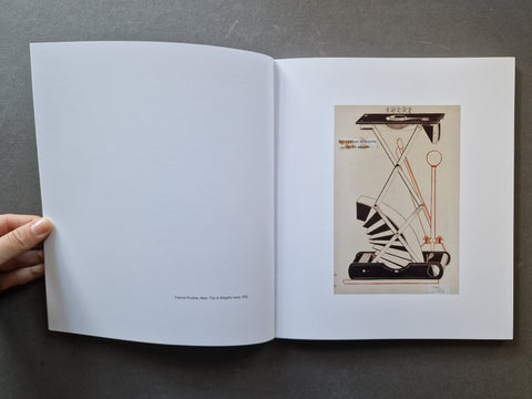 An open book showing a white spread with a vintage technical illustration of an old analogue camera