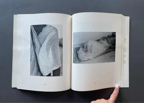 An open book or art print showing two black-and-white photographic pages, photographed from above on a dark gray surface.
