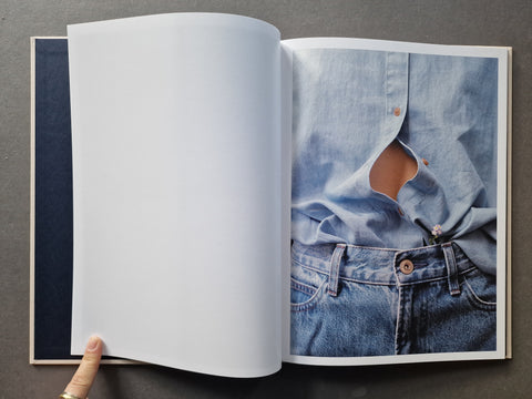An open book, showing a photo on the right page of a light blue denim shirt and jeans