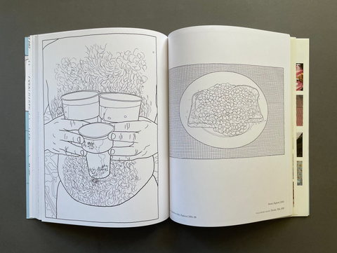 An open art book displayed flat on a dark gray surface, showing two illustrated pages with black line drawings on white paper.