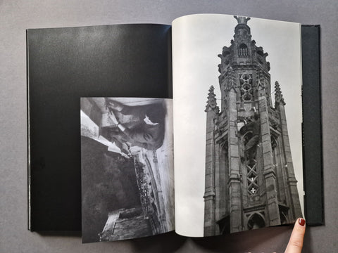 An open black-and-white art book, showing a large architectural photograph on the right page and a smaller inset photo on the left.
