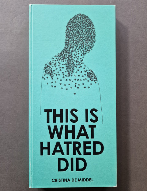 The book cover of 'This Is What Hatred Did' by Cristina De Middel, featuring a light turquoise background with a black dotted silhouette of a person and bold black text, photographed flat on a neutral gray surface.