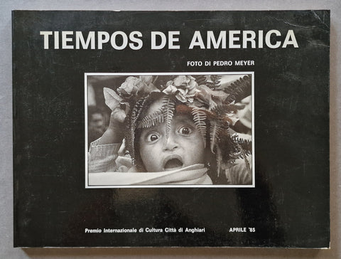 A book cover titled 'TIEMPOS DE AMERICA' with a black background, large white title text, a central black-and-white photograph, and smaller white text including 'FOTO DI PEDRO MEYER' and 'APRILE '85'.