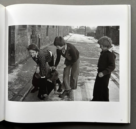 Black and white photo of three people in an alleyway on a book page.