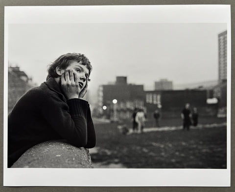Black and white photo of a person leaning on a wall with a cityscape in the background