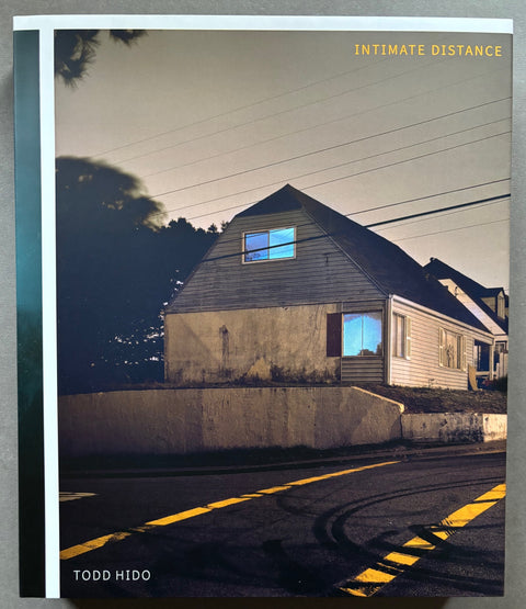Book titled 'Intimate Distance' by Todd Hido with a cover featuring the image of a house on a street with it's windows illuminated.