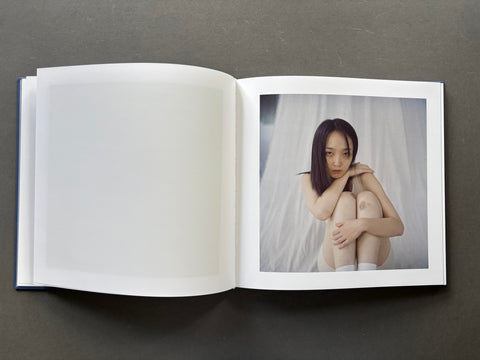Open book showing a photograph of a person against a white curtain on a dark background