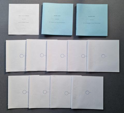 A set of printed booklets or envelopes laid out on a dark gray background, including three light blue covers at the top and multiple white folded sheets below with small blue circular logos.