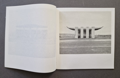 An open book, showing a black-and-white architectural photograph printed on the right page and a faintly visible page on the left.