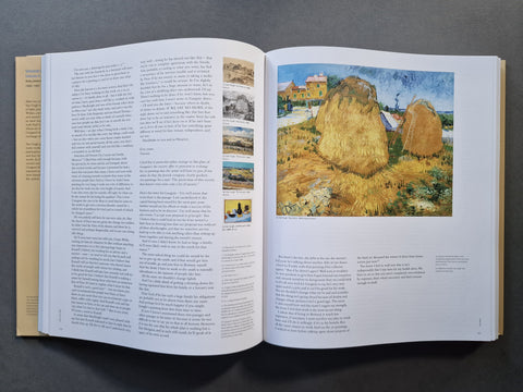 An open book spread showing printed text on both pages and a reproduction of Vincent van Gogh's 'Haystacks' painting on the right page, photographed on a dark gray surface.