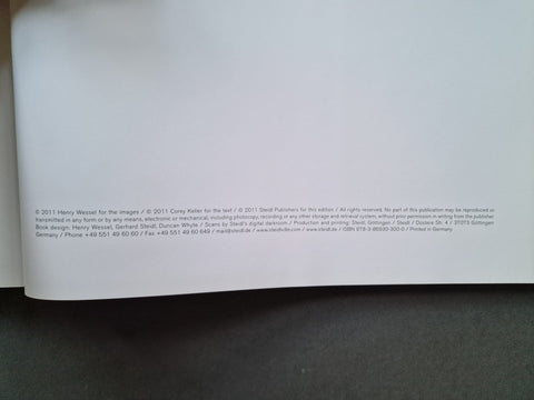 A close-up of a white printed page with small copyright and publisher text at the bottom, photographed against a dark gray surface.