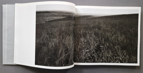 An open book spread showing a landscape photograph of a field.