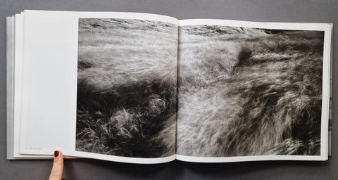 an open book spread showing a landscape photograph of what appears to be a field with the grass caught in movement