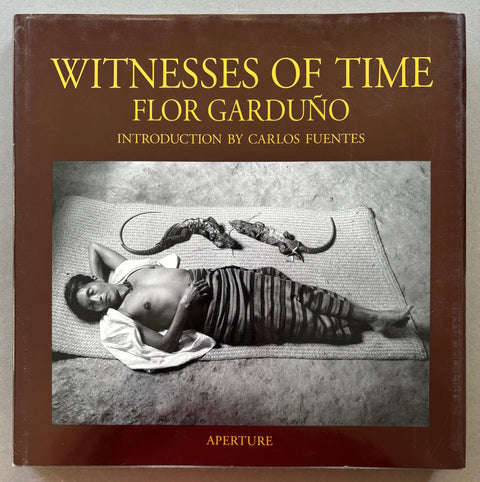 Book titled 'Witnesses of Time' by Flor Garduno with a brown cover featuring a black and white image of a man sleeping next to 2 reptiles.