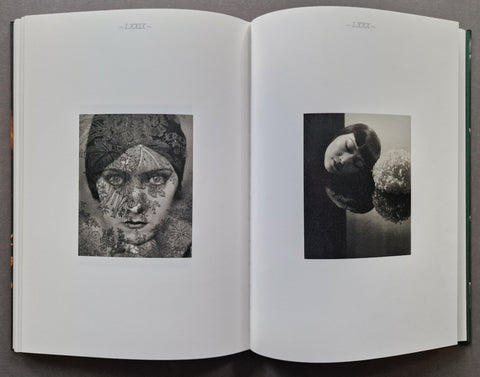 An open book showing two printed black-and-white portrait photographs on white pages, photographed from above on a dark surface.