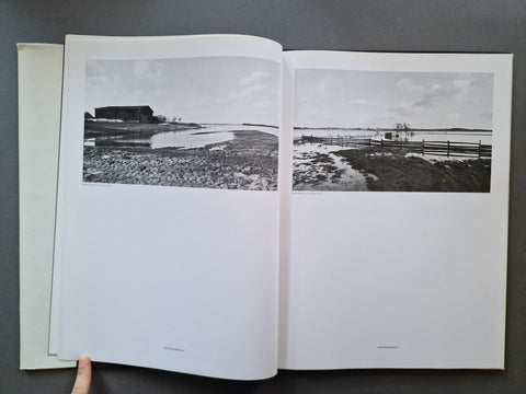 An open book, showing two printed black-and-white landscape photographs spread across the pages.