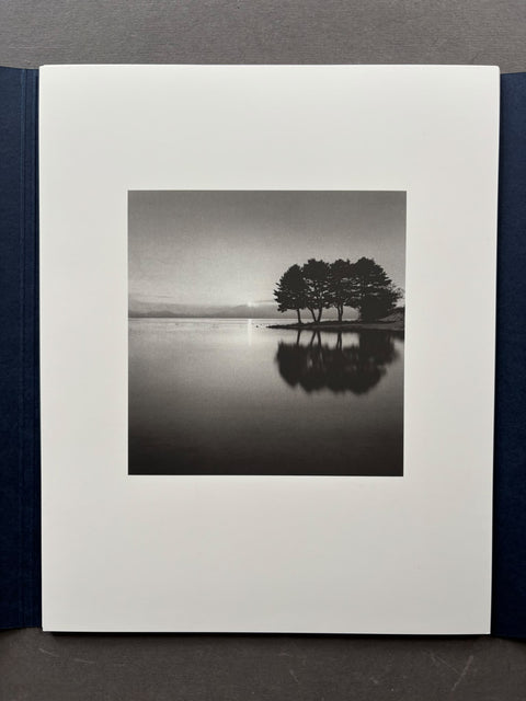 A black and white landscape photograph print of a landscape with trees and a lake