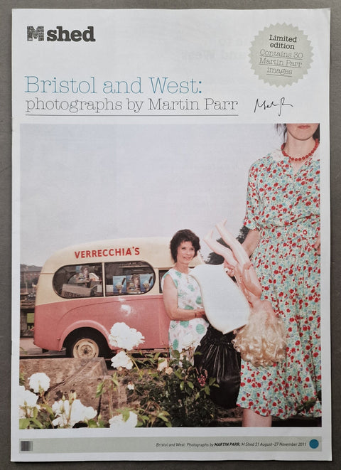 A flat lay photograph of a M shed magazine cover featuring Martin Parr's 'Bristol and West: photographs by Martin Parr' collection, with a vintage pink and cream bus, women in floral dresses, and white flowers.
