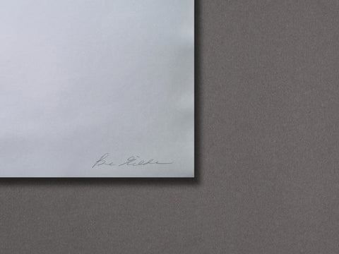 A close-up of a white sheet of paper with a faint signature near the bottom left corner, set against a textured dark gray background.