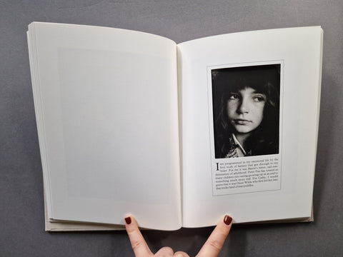 An open book, showing blank white pages on the left and a black-and-white portrait page with text on the right, set against a dark gray background.