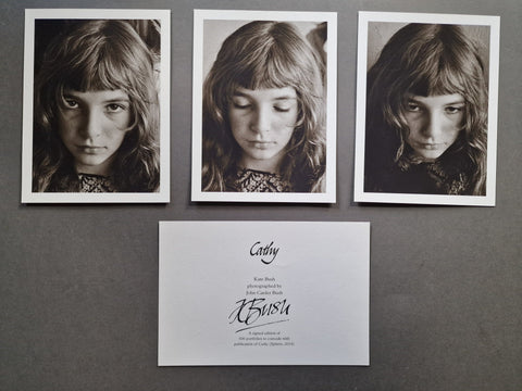 Three black-and-white portrait photographs of a young girl (Kate Bush) are arranged above a signed card of authenticity on a dark gray background.