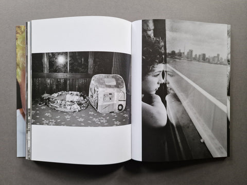An open book, showing two printed pages with black-and-white photographs. The left page contains a photo of a kid in an inflatable pool and the right page shows a black-and-white portrait of a kid looking out a window beside a city skyline.