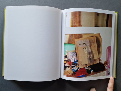 An open book , showing a mostly blank white left page and a printed interior spread with several small photographs on the right page.