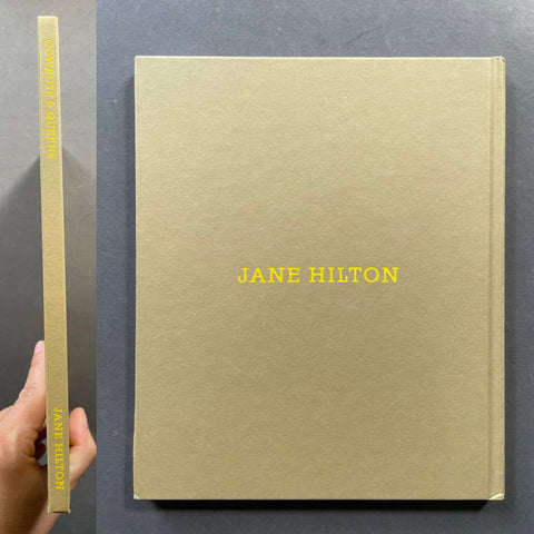 A hardcover book titled 'JANE HILTON' by Jane Hilton, shown from the front and spine. The cover is a textured light tan/beige with the title printed in yellow.