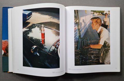 An open book spread showing two printed photographs side by side on white pages, photographed from above on a dark gray surface.