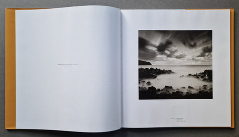 An open hardcover book, showing a black-and-white landscape photograph printed on the right page.