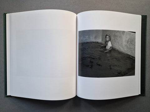 An open book, showing a black-and-white photograph printed on the right page. The left page is blank, and the book has a dark green cover edge visible along the sides.