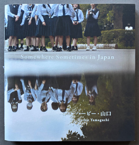 Book titled 'Somewhere Sometimes in Japan' by Herbie Yamaguchi with a cover featuring the image of a group of school children and their reflection in a pool of water.