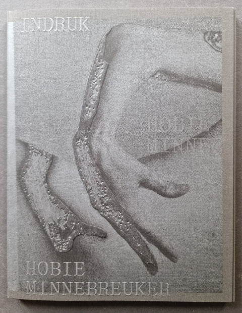 A book cover featuring a monochrome photograph of an arm with the text 'INDRUK' at the top and 'HOBIE MINNEBREUKER' at the bottom.