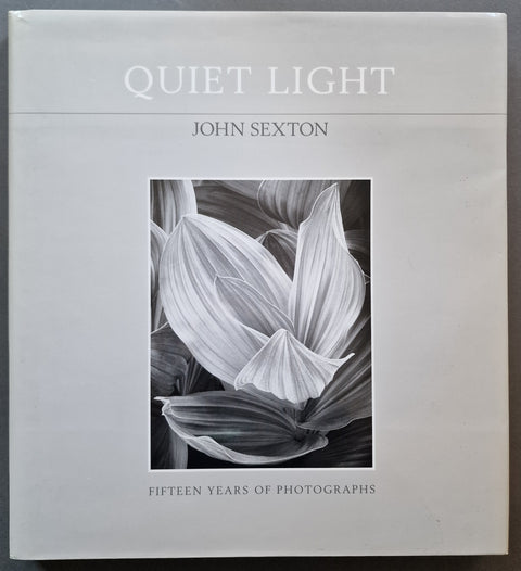 The front cover of the book 'Quiet Light: Fifteen Years of Photographs' by John Sexton, featuring a black and white floral photograph in the center on a light gray background.