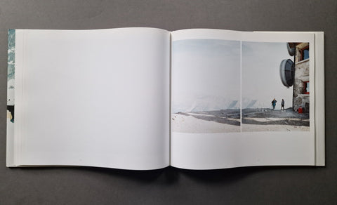 An open hardcover book, showing a mostly blank left page and a two-photo spread on the right page with a snowy landscape and a building scene.