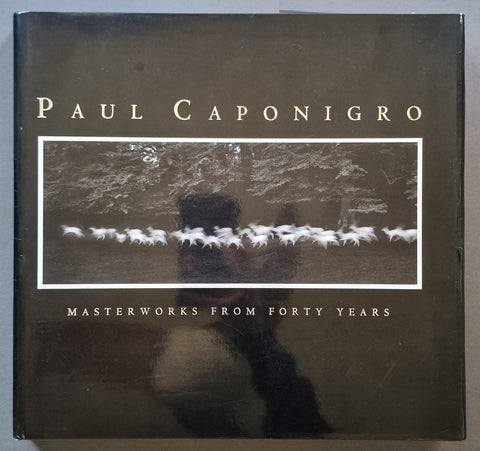 A hardcover book titled 'PAUL CAPONIGRO MASTERWORKS FROM FORTY YEARS' with a dark cover and a central black-and-white photograph of a herd of horses.