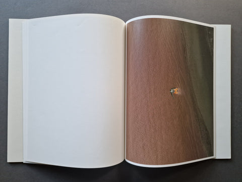 A book spread showing a large-scale negative of a person on the beach in the water on the right page