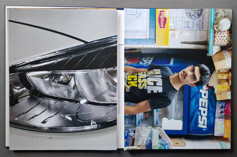An open book photographed from above on a dark surface. The left page shows a close-up of a car headlight and grille.