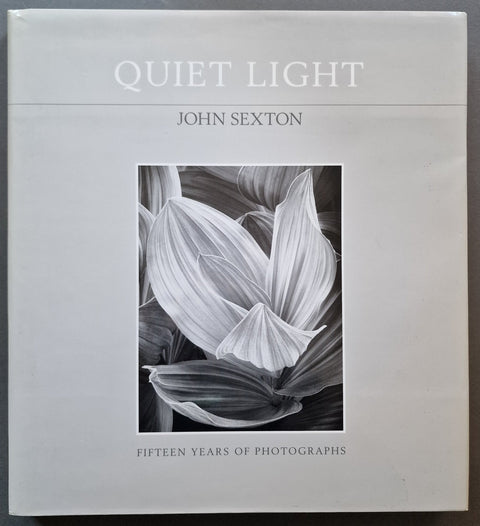 The front cover of the book 'Quiet Light: Fifteen Years of Photographs' by John Sexton, featuring a black and white floral photograph in the center on a light gray background.